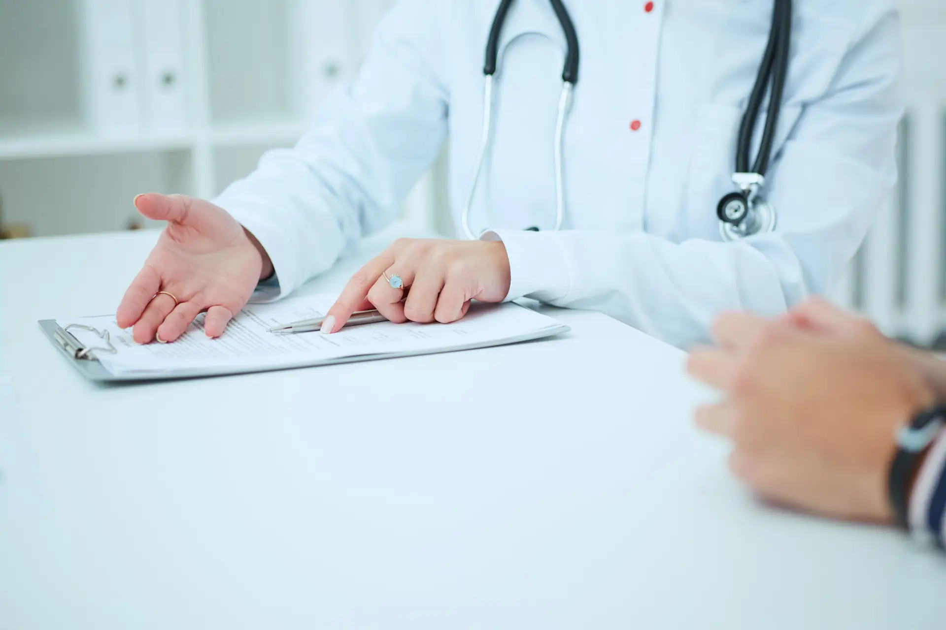 Dottoressa in camice bianco spiega documenti clinici a paziente per prevenire errori medici.